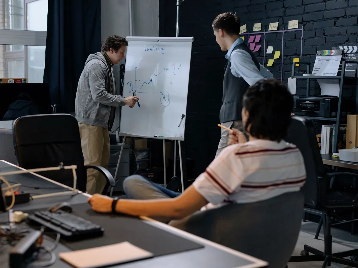 Équipe d'entreprise en séance de brainstorming devant un tableau blanc, dans un bureau moderne