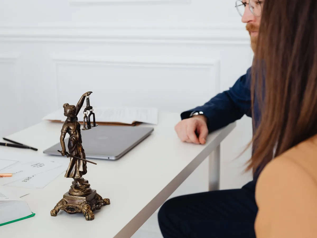 Cadre professionnel avec des avocats discutant de documents juridiques près d'une statue Lady Justice