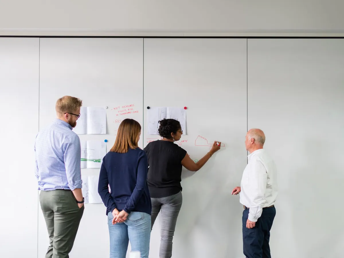 Équipe diversifiée planifiant une stratégie devant un tableau blanc dans un bureau
