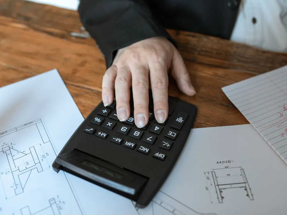 Main utilisant une calculatrice pour des calculs d'architecture sur des plans