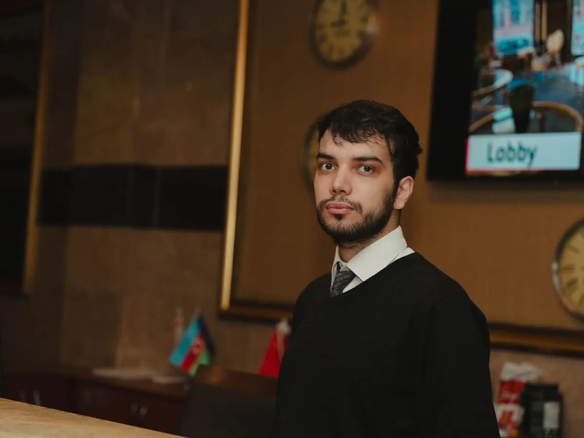 Réceptionniste d'hôtel debout derrière le comptoir du hall, prête à accueillir les clients