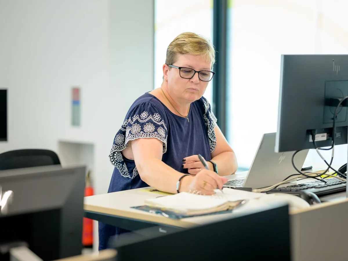 Femme professionnelle à lunettes travaillant à un bureau avec un ordinateur portable et un carnet