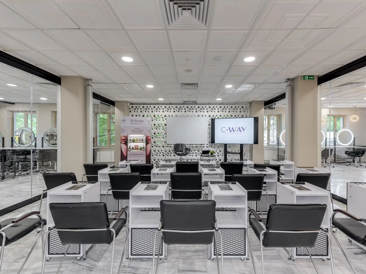 Espace de formation lumineux et moderne d'un salon de coiffure, avec rangées de fauteuils noirs et postes équipés