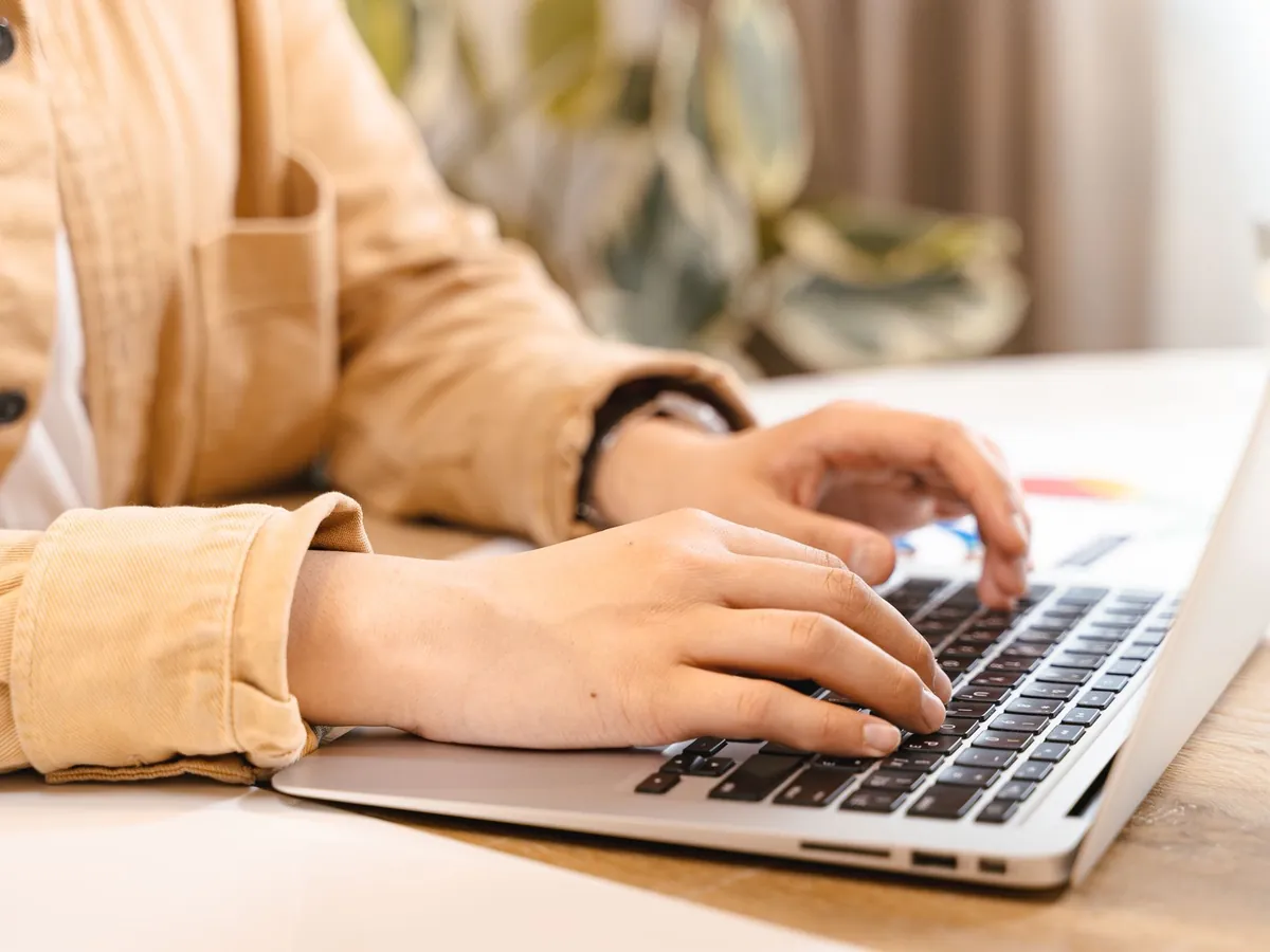 Gros plan de mains tapant sur un ordinateur portable dans un espace lumineux, travail et technologie