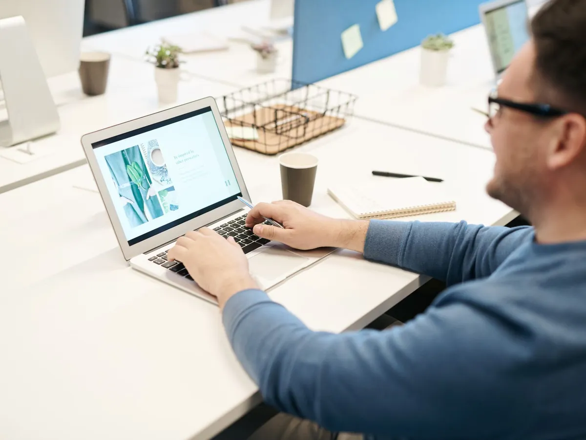 Homme adulte concentré sur l'écran de son ordinateur portable, dans un bureau