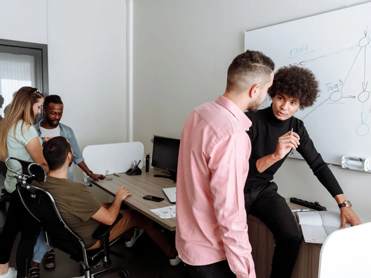 Équipe diversifiée en discussion de travail au bureau, échangeant des idées sur un projet