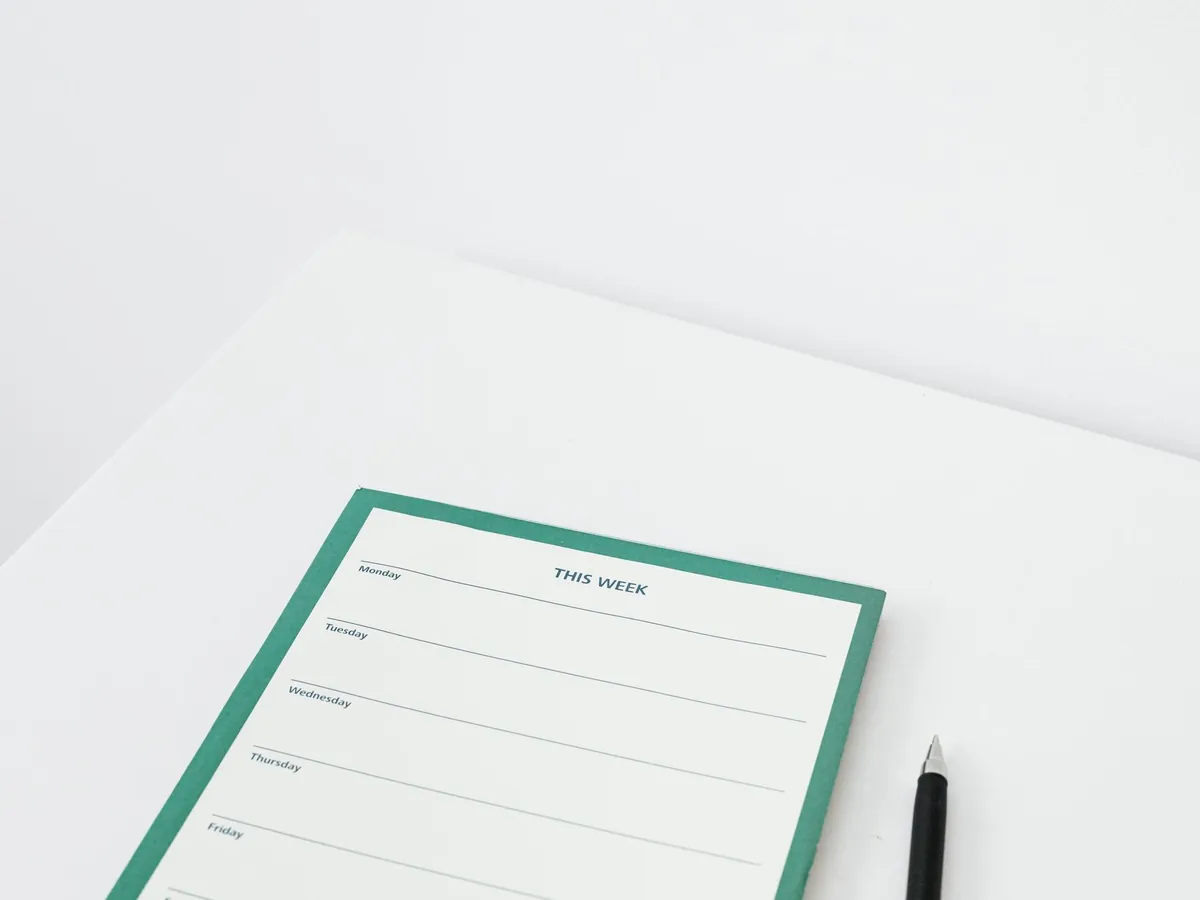 Agenda hebdomadaire épuré et minimaliste avec un stylo, posé sur un bureau blanc