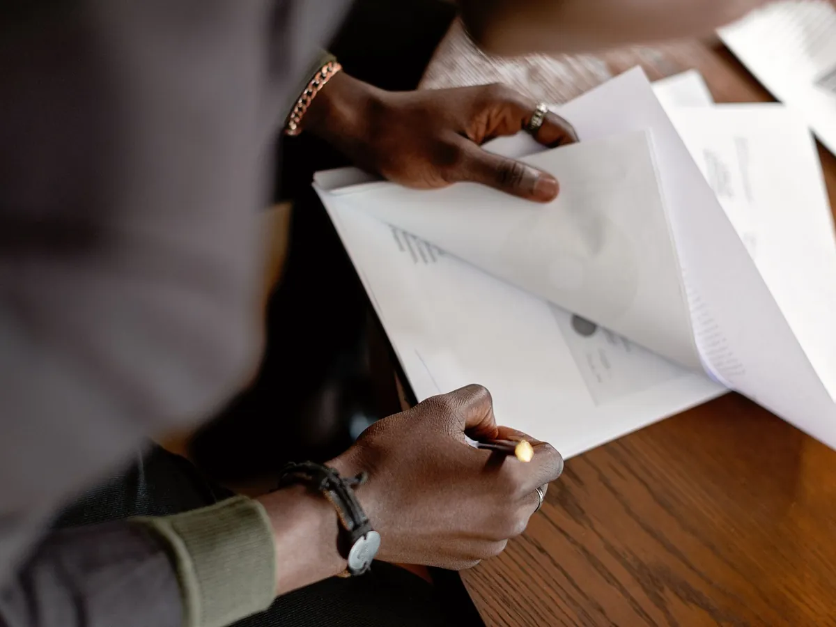 Adulte afro-américain corrigeant des documents au crayon à son bureau, gros plan sur les mains