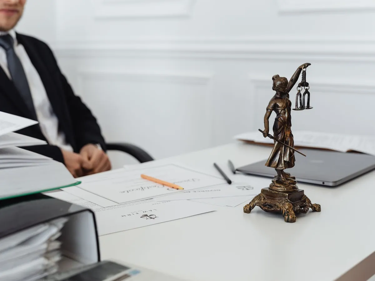 Espace de travail juridique avec une statue de la Justice, des documents et un ordinateur portable