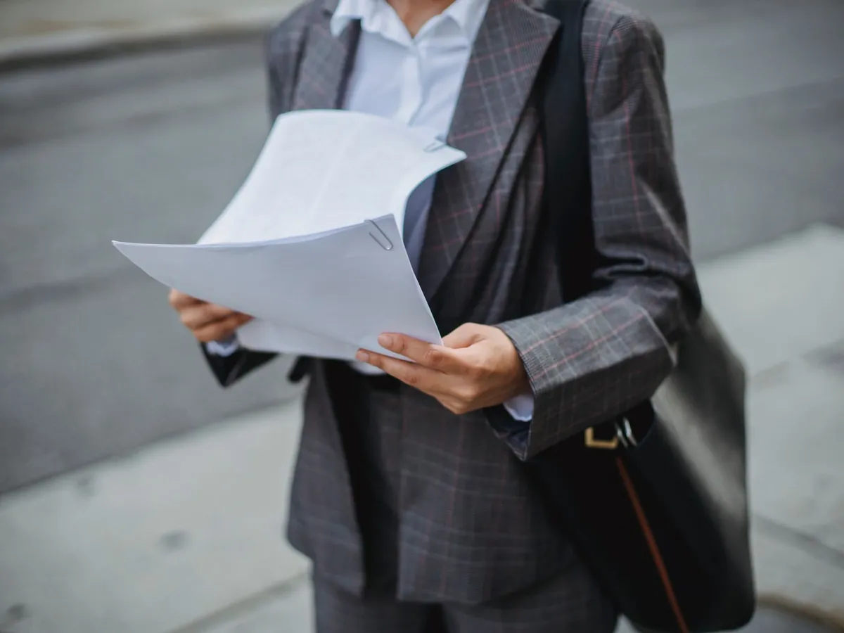 Femme d'affaires professionnelle examinant des documents en extérieur, dans un environnement urbain
