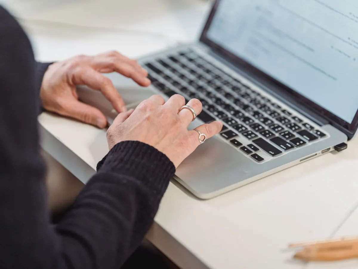 Gros plan de mains tapant sur le clavier d'un ordinateur portable dans un bureau à domicile