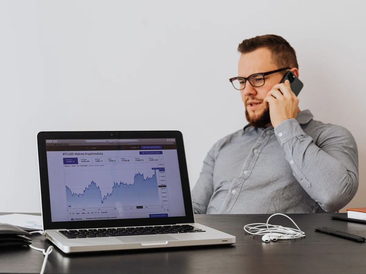Professionnel au bureau analysant les tendances des cryptomonnaies sur son ordinateur, au téléphone