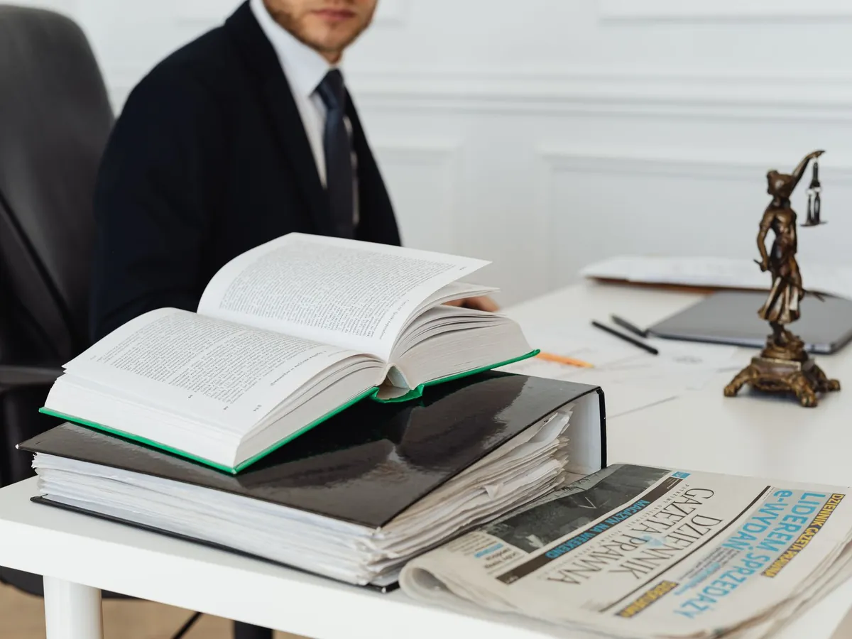 Avocat assis à son bureau, entouré d'ouvrages juridiques, de documents et d'un journal