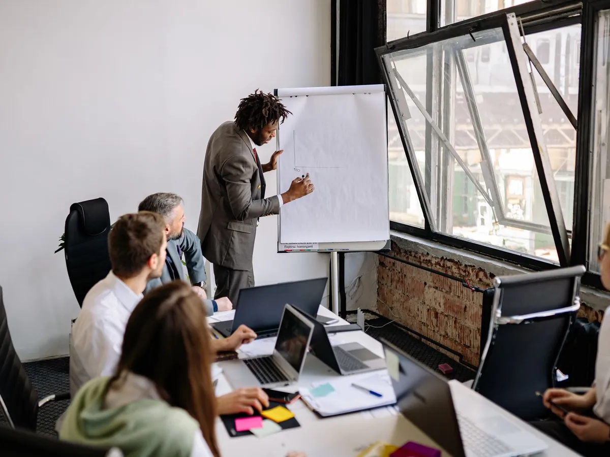 Équipe diversifiée en réunion d'affaires avec une présentation dans un bureau moderne