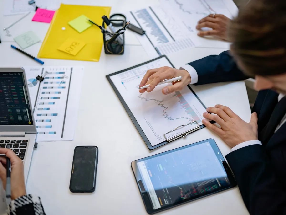 Équipe analysant des graphiques financiers et des données numériques sur tablettes, au bureau