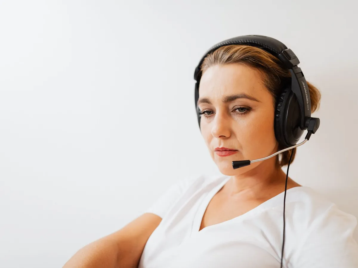 Femme concentrée avec casque téléphonique travaillant au support client, sur fond blanc