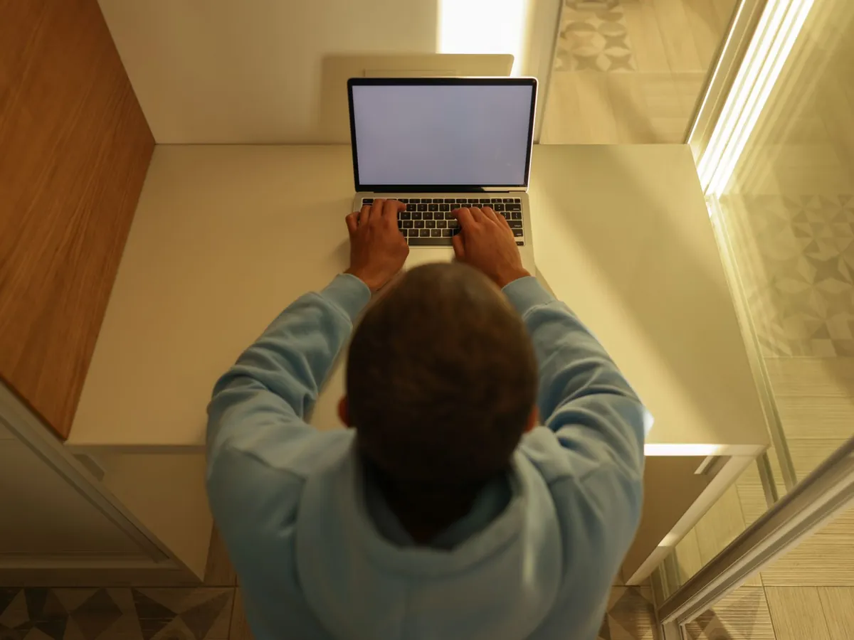 Vue de dessus d'une personne tapant sur un ordinateur portable à son bureau