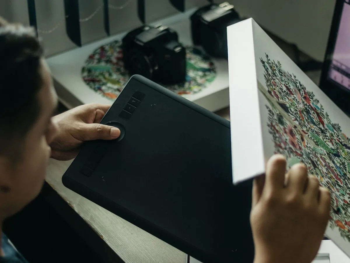 Gros plan d'une artiste numérique travaillant sur une tablette graphique, en intérieur
