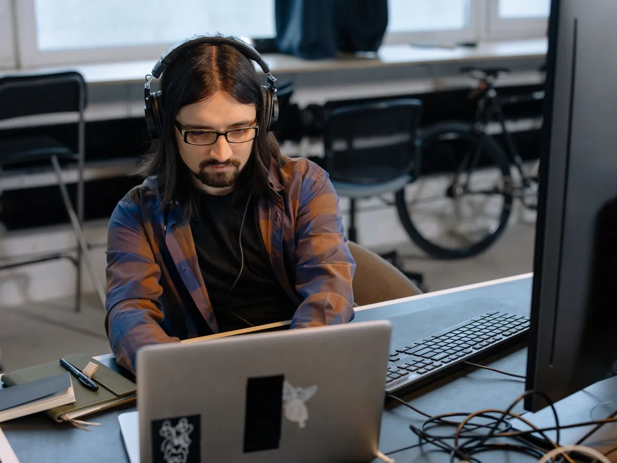 Développeur barbu au casque, codant sur son ordinateur portable dans un bureau moderne
