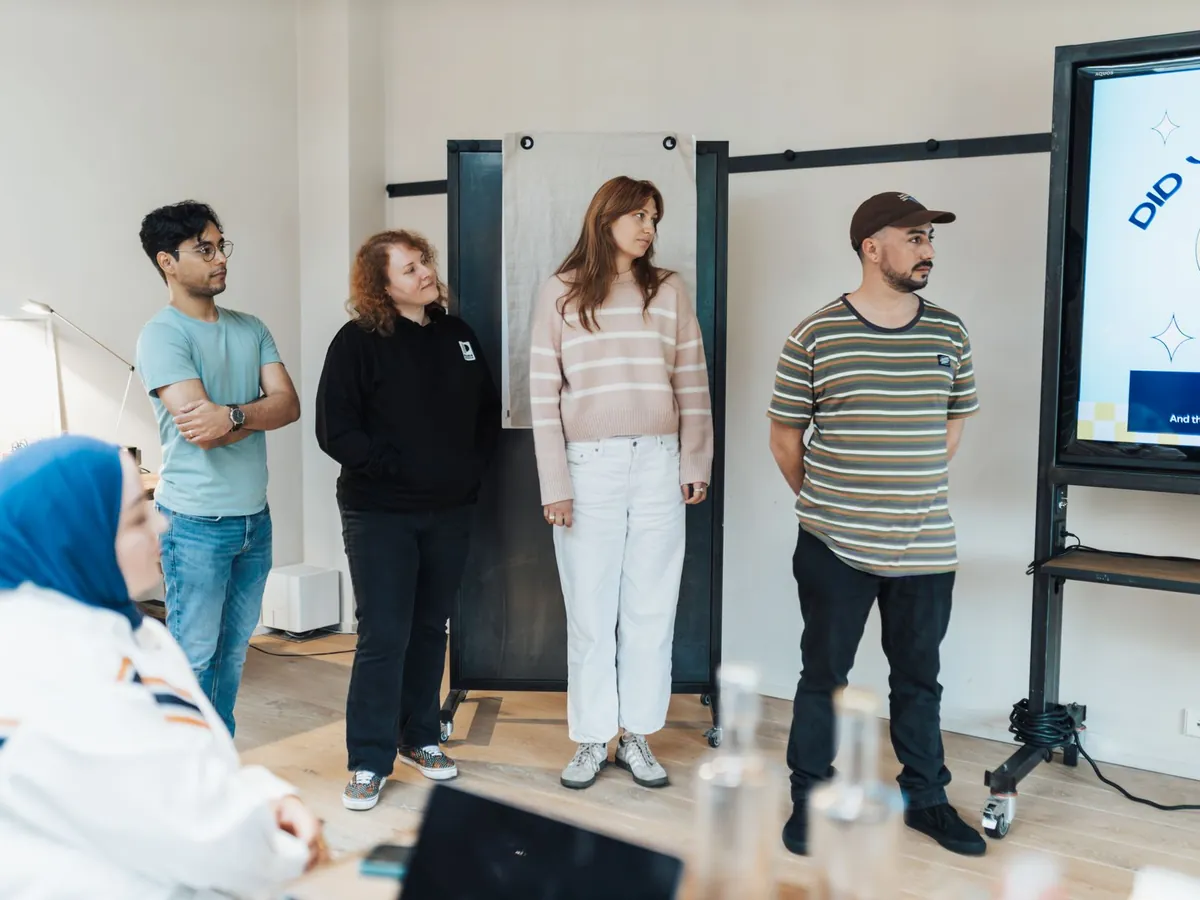 Groupe d'adultes d'horizons variés suivant attentivement une présentation dans un bureau lumineux