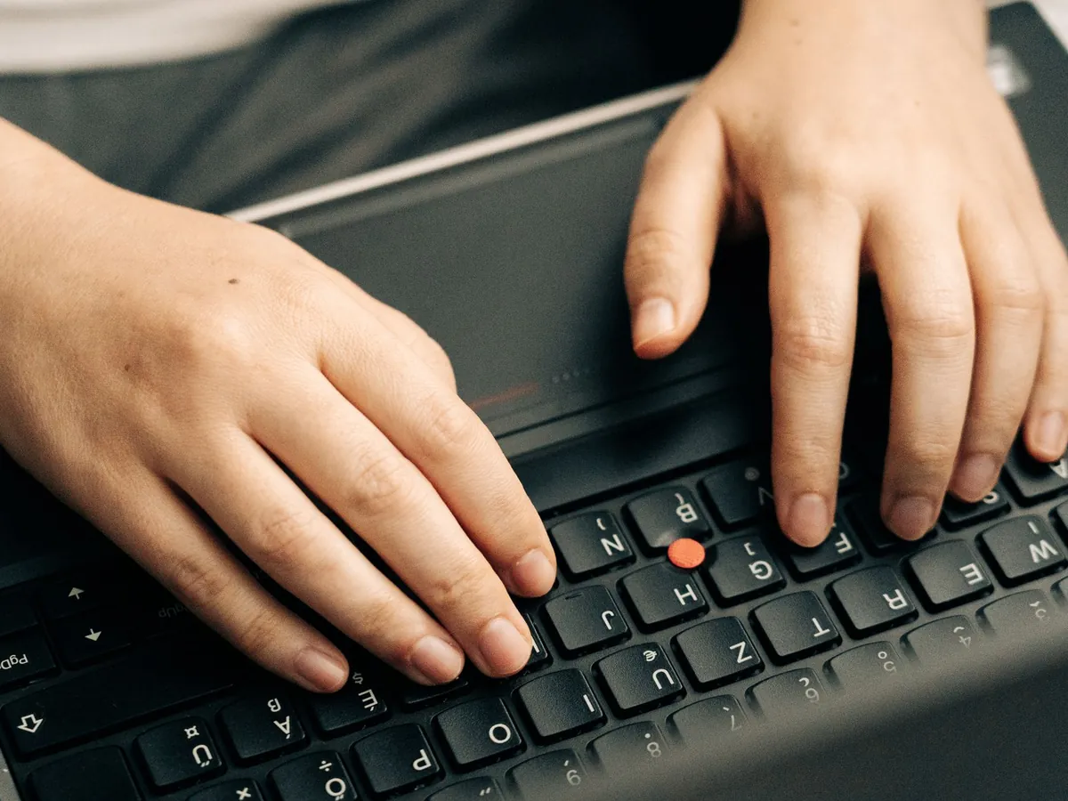 Gros plan de mains tapant sur le clavier d'un ordinateur portable noir, symbole de productivité