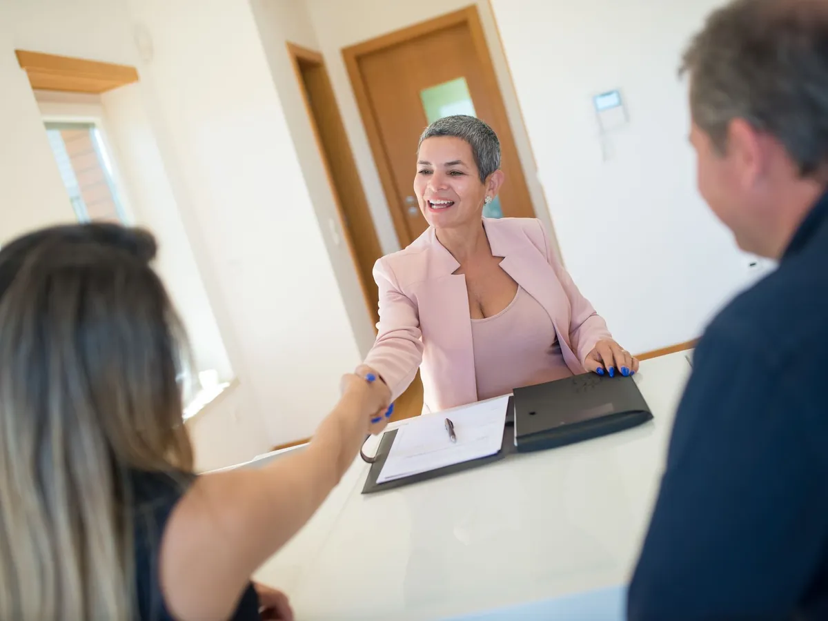 Agent immobilier concluant une transaction avec ses clients, dans une atmosphère de confiance