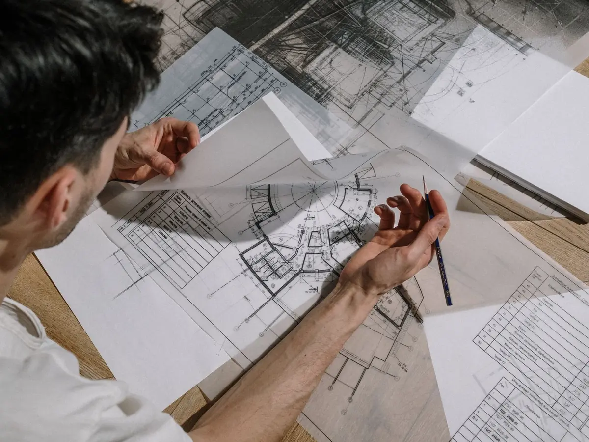 Architecte étudiant et esquissant des plans d'architecture détaillés, en intérieur