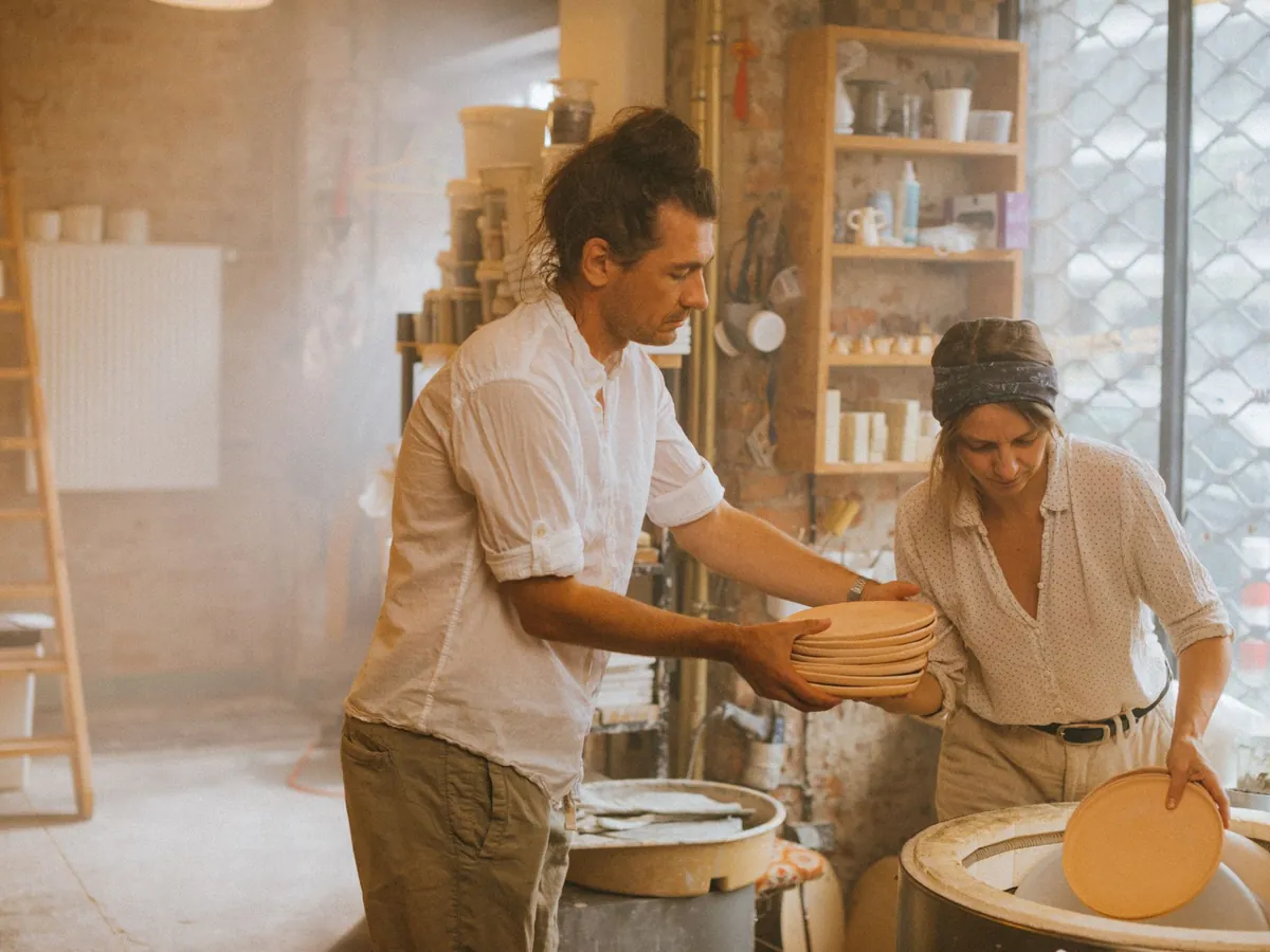 Couple façonnant ensemble de la céramique dans un atelier ensoleillé