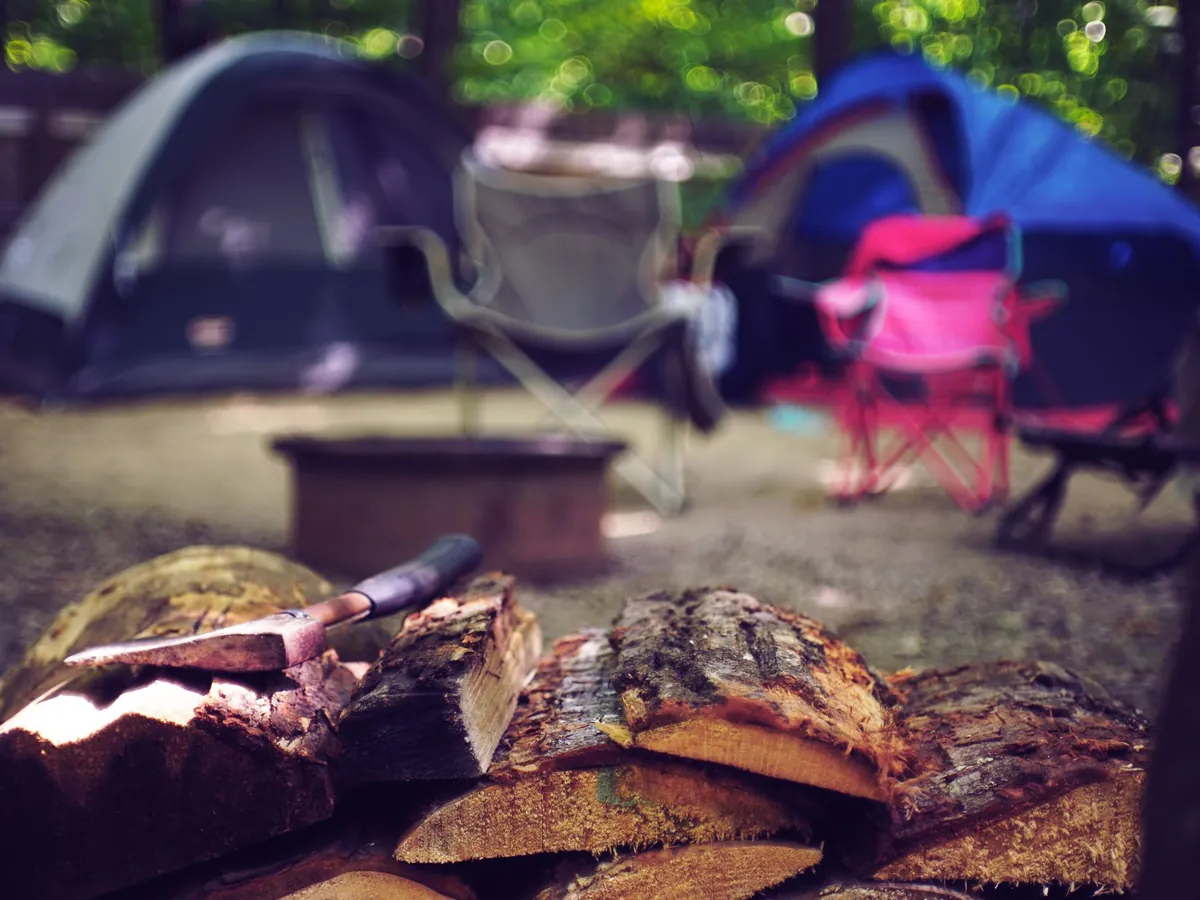 Campement paisible avec tentes, chaises et tas de bois de chauffage, pour un séjour d'été