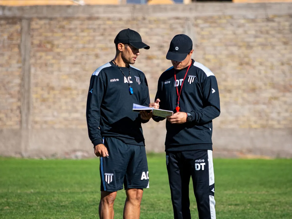 Deux entraîneurs de football analysant leur stratégie sur le terrain, en journée