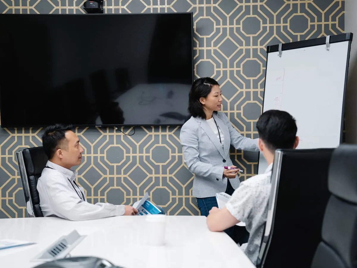Professionnel présentant un exposé dans un espace de bureau moderne, collègues attentifs