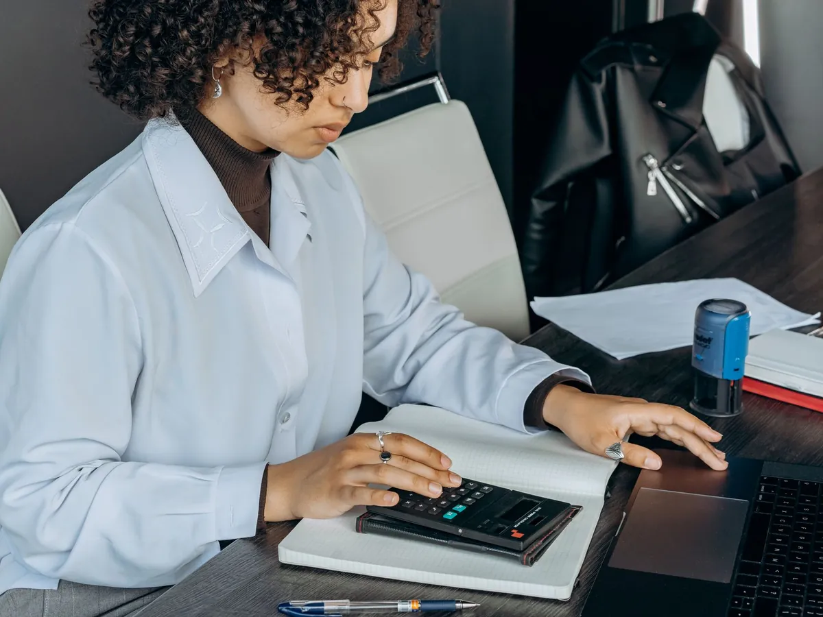 Jeune femme au bureau utilisant une calculatrice pour des calculs financiers