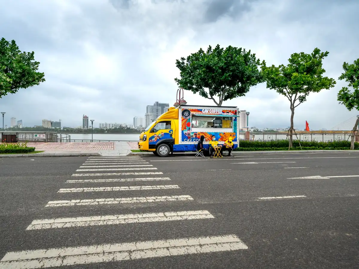 Food truck coloré garé dans une rue déserte, face à une vue pittoresque sur le fleuve
