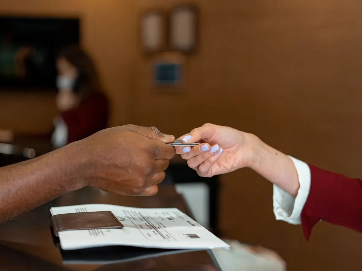 Gros plan d'une réceptionniste d'hôtel encaissant une carte bancaire lors de l'enregistrement