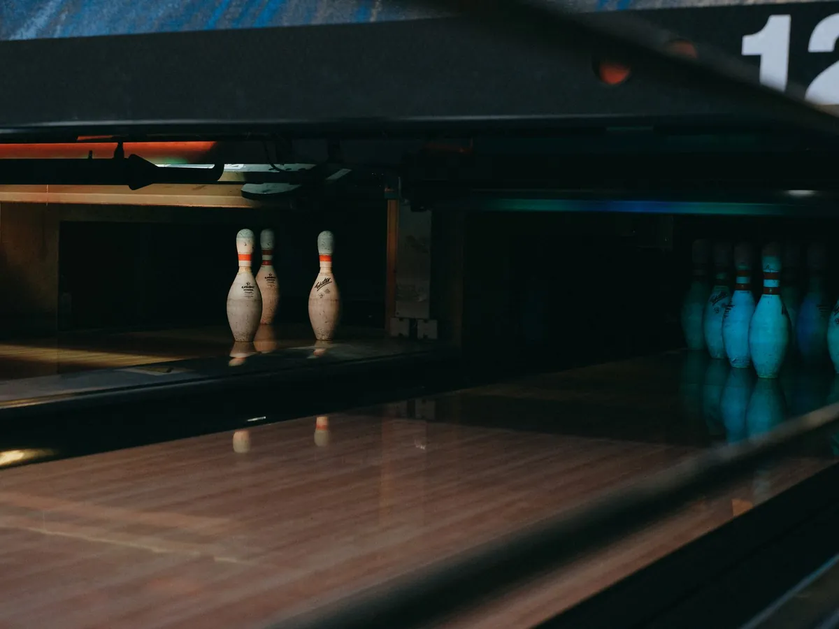 Allée de bowling faiblement éclairée, quilles alignées prêtes pour un strike