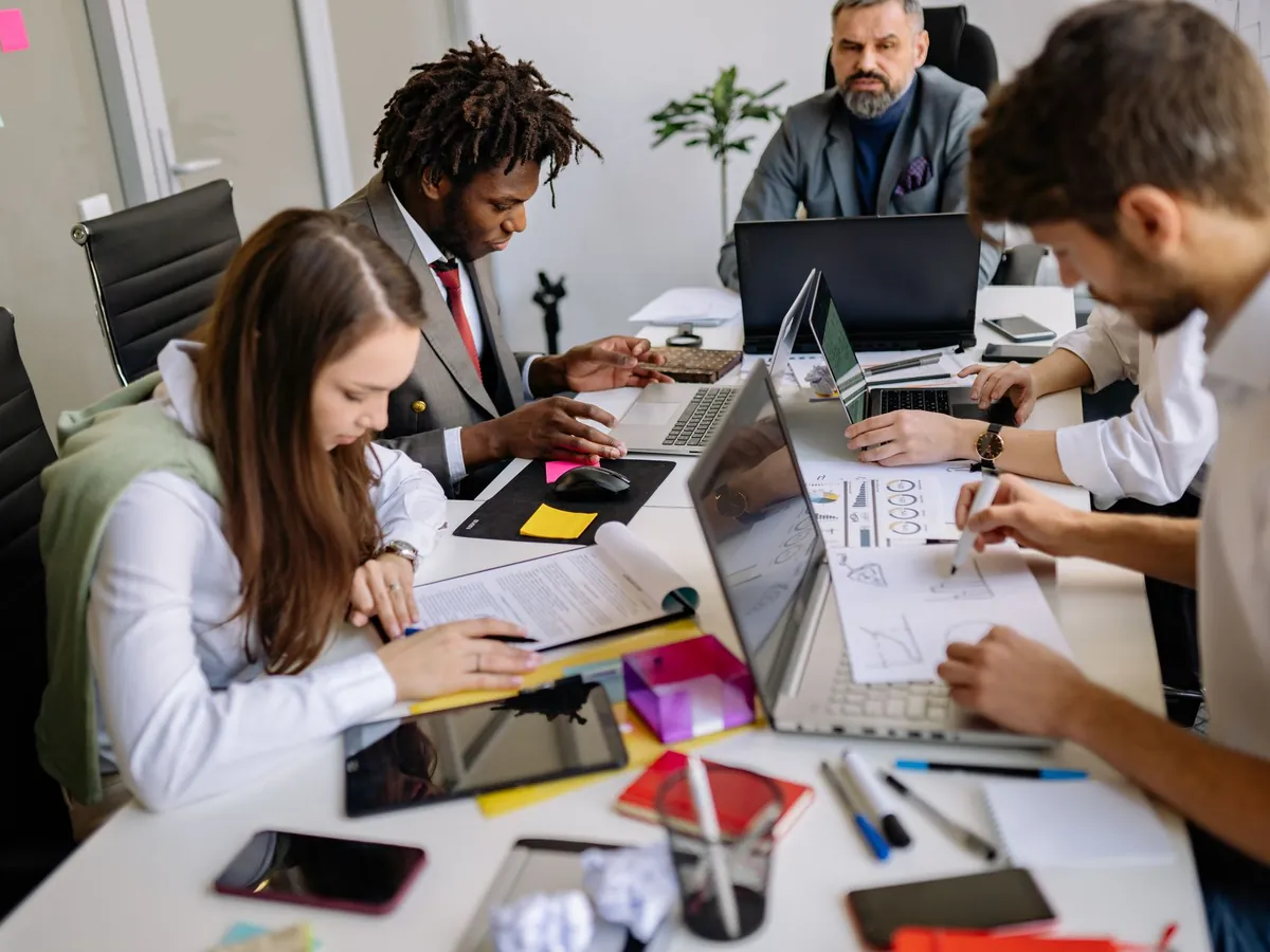 Équipe de professionnels collaborant autour d'une table dans un bureau moderne, autour de projets