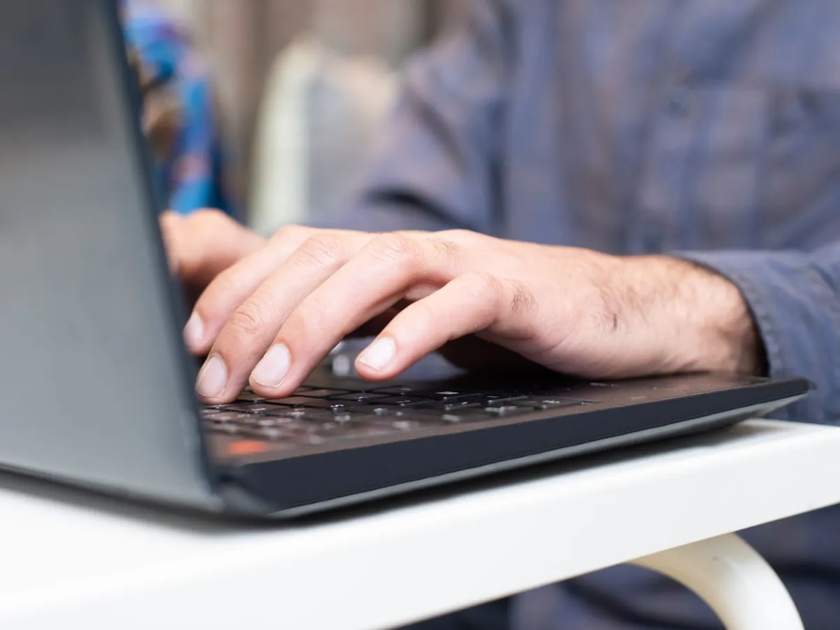 Gros plan de mains tapant sur le clavier d'un ordinateur portable, dans un cadre professionnel