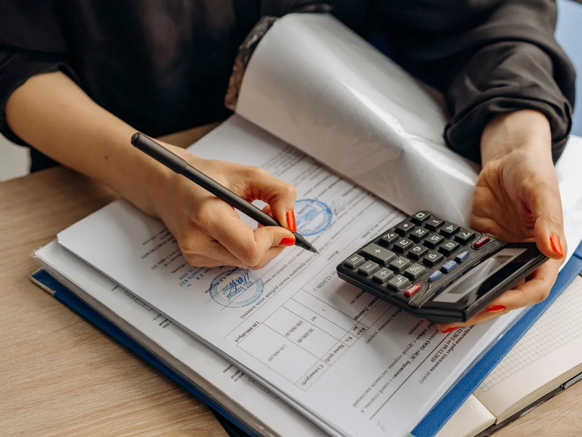 Comptable utilisant une calculatrice et signant des documents, dans le cadre d'une analyse financière