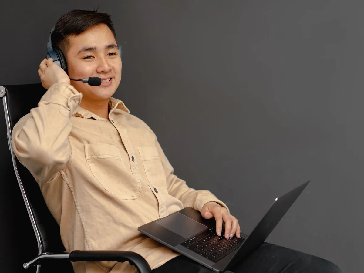 Agent du service client souriant, utilisant un ordinateur portable et un casque en intérieur