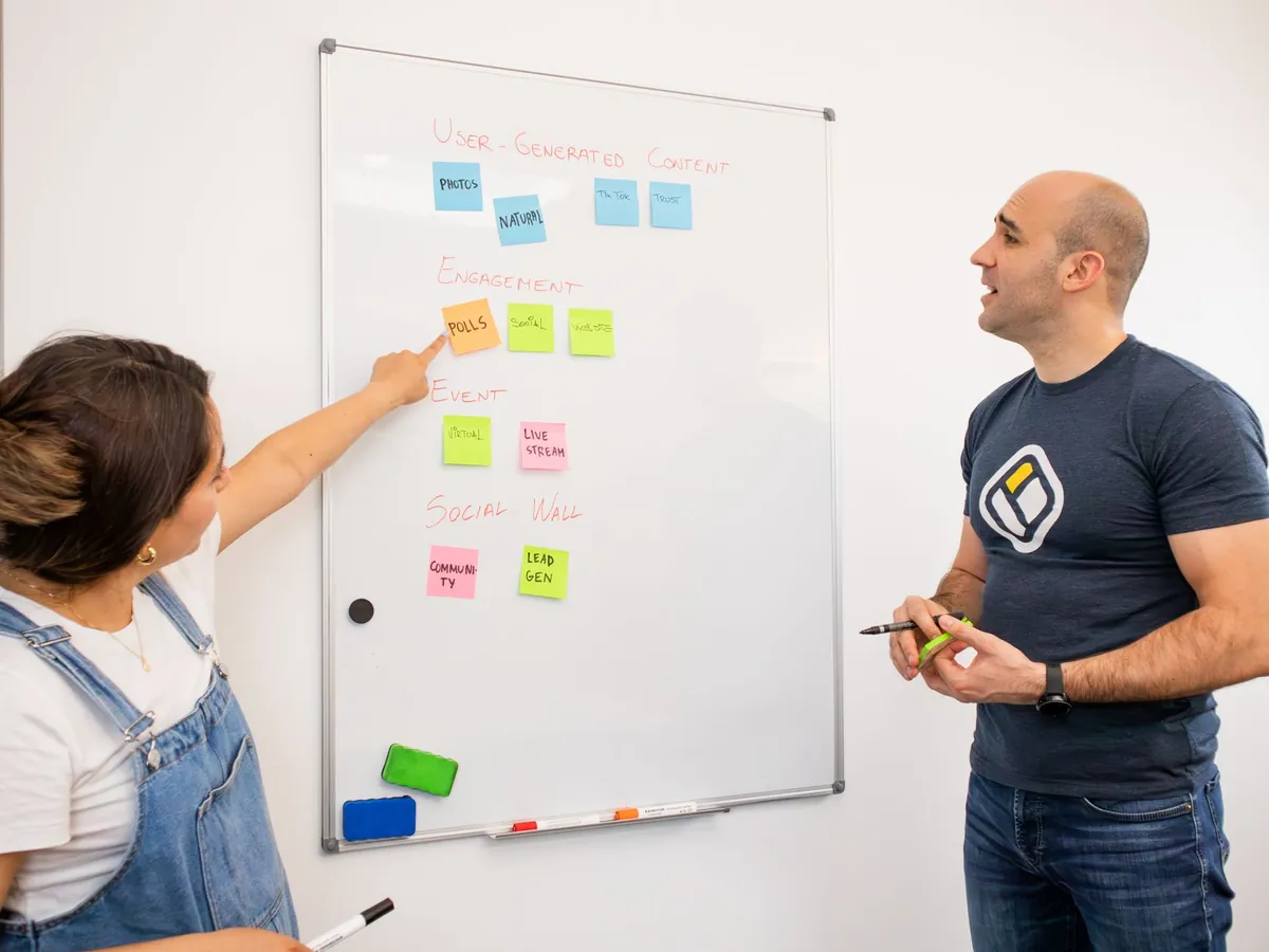 Deux collègues font un brainstorming devant un tableau blanc couvert de post-it colorés pour un projet