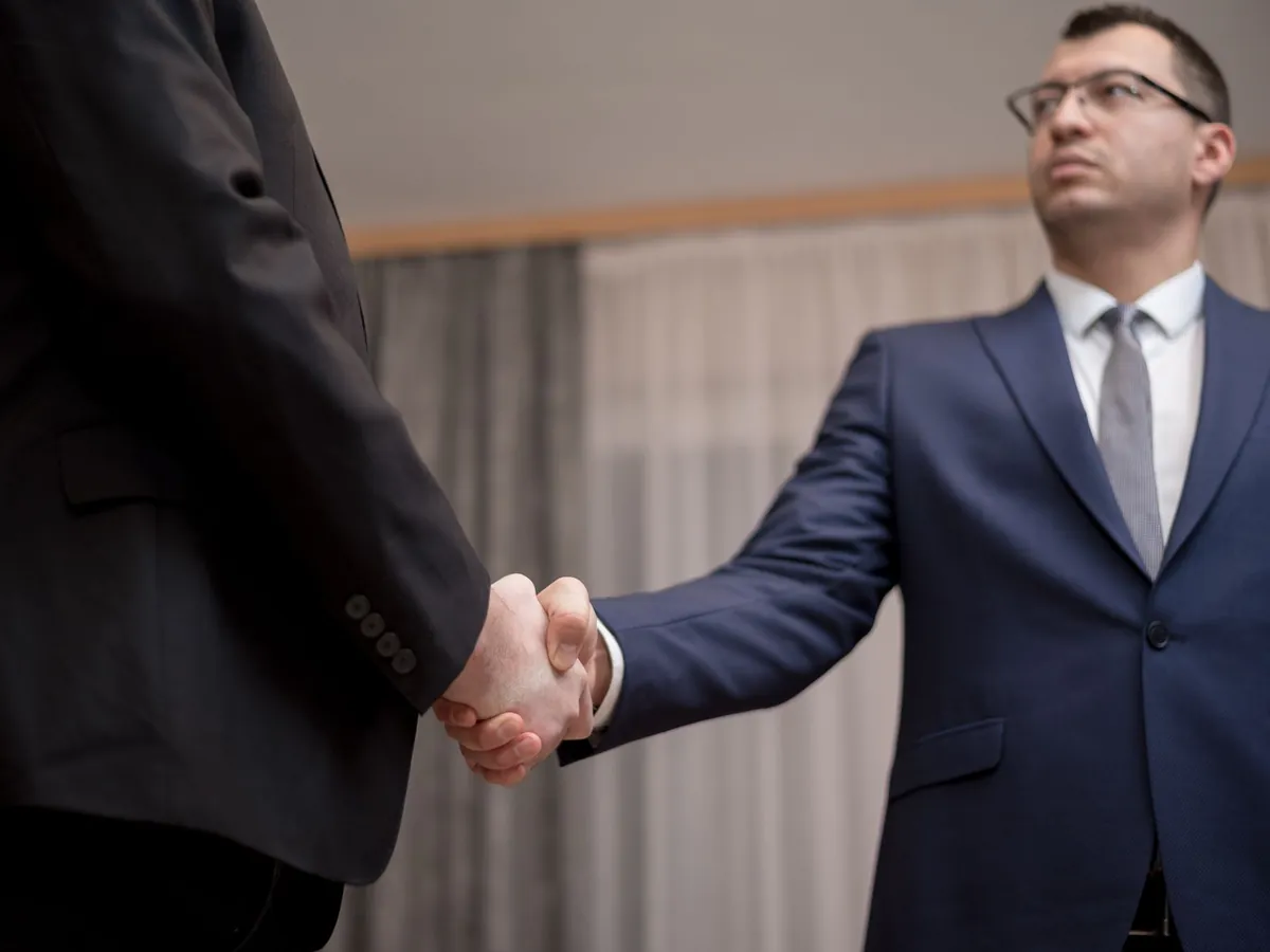Deux hommes d'affaires en tenue formelle se serrant la main lors d'une réunion