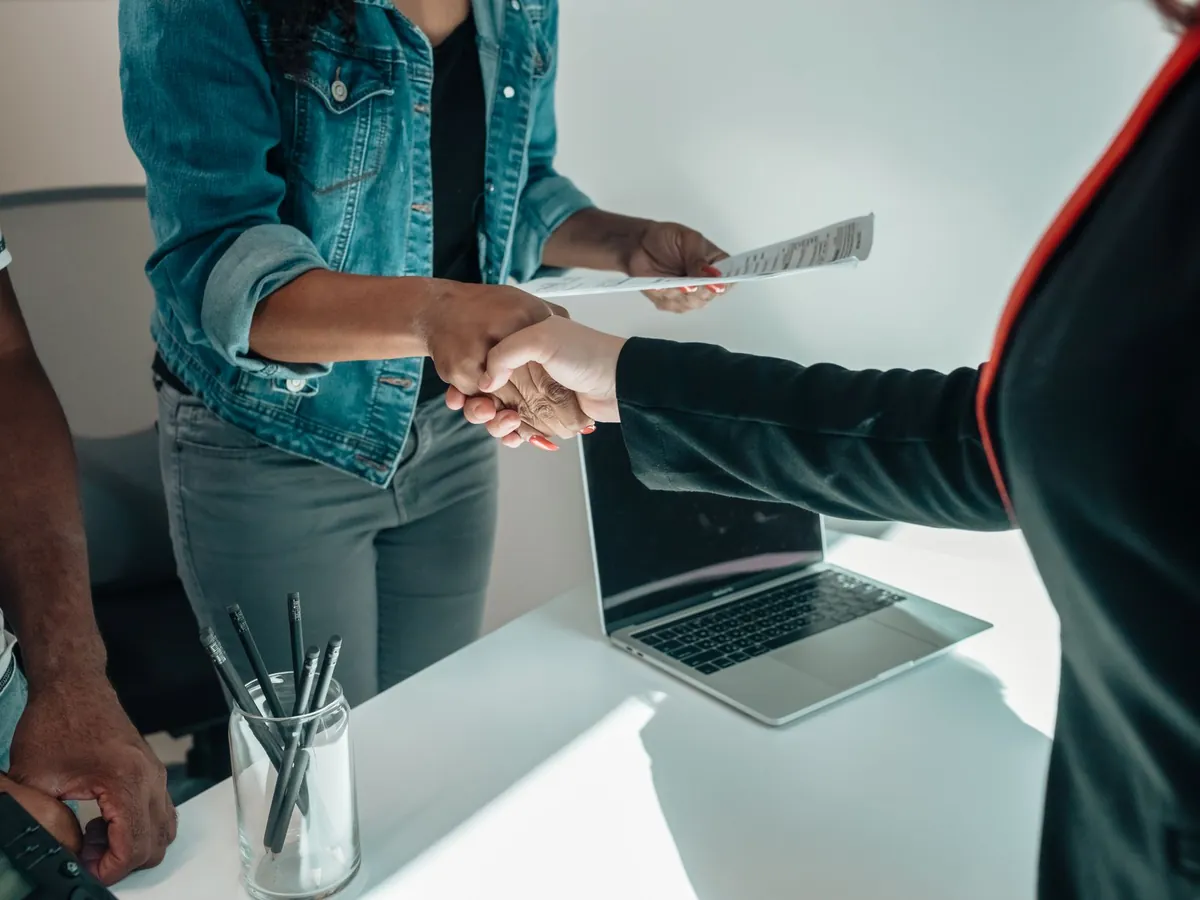 Deux personnes se serrant la main par-dessus un bureau, symbole d'un partenariat