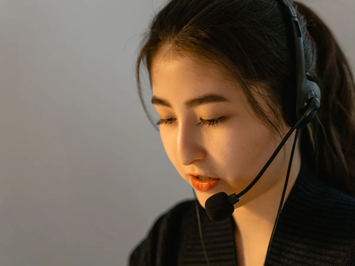 Jeune femme concentrée avec casque, travaillant au support client et parlant attentivement