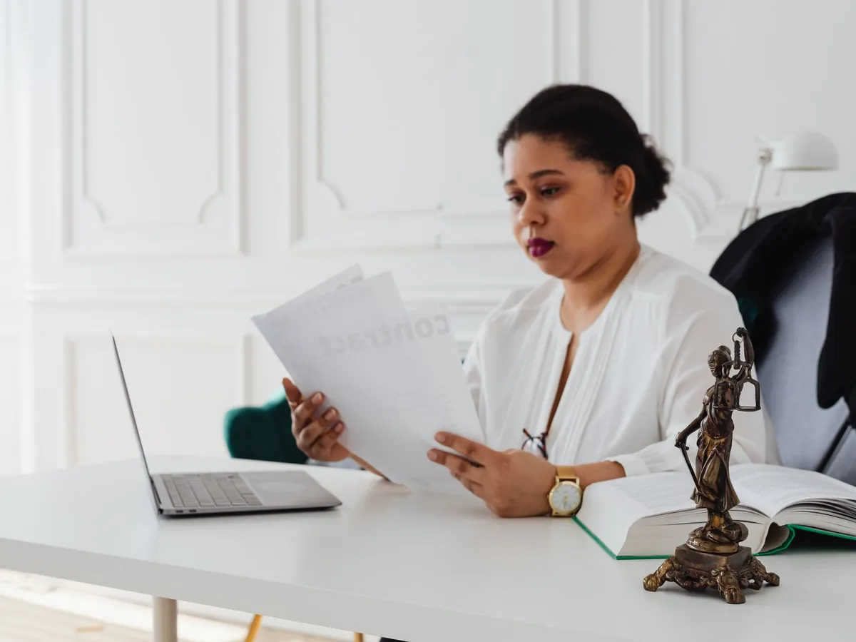 Avocate noire lisant des documents juridiques à son bureau, dans un bureau moderne