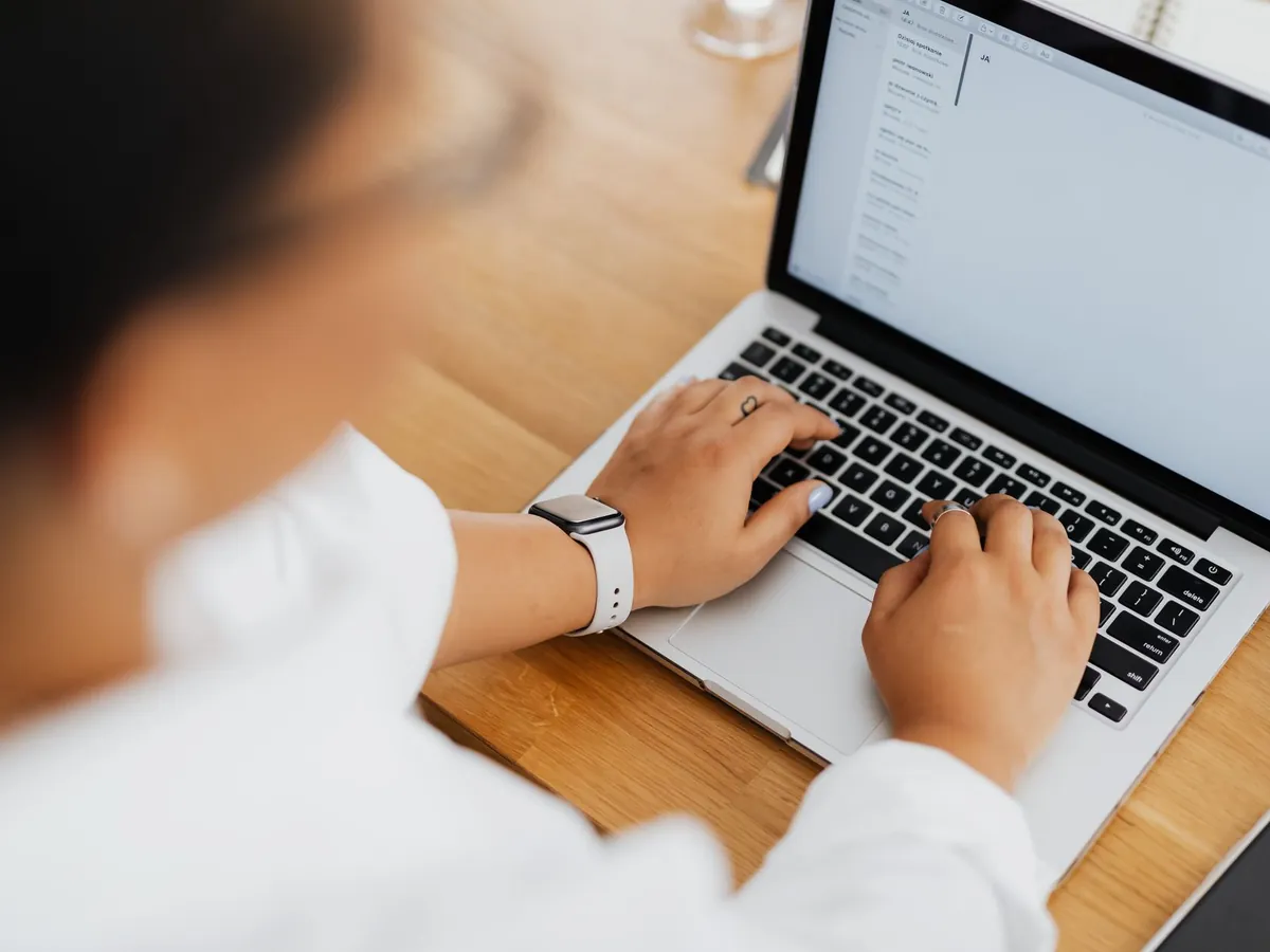 Vue en plongée d'une personne tapant sur son ordinateur portable, focus sur les mains et le clavier