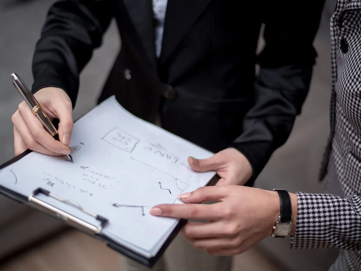 Gros plan de professionnels collaborant, prenant des notes sur une planchette à pince