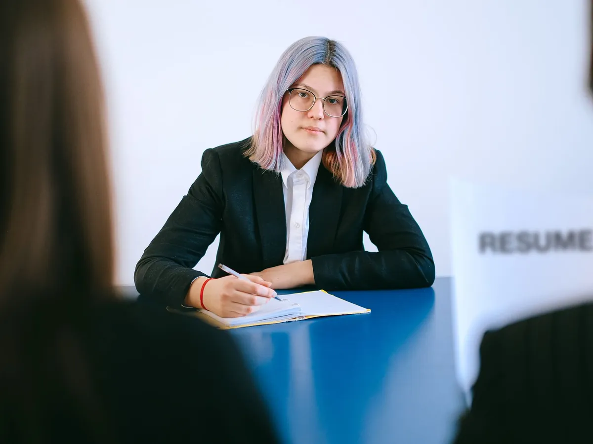 Jeune femme aux cheveux colorés prenant des notes pendant un entretien d'embauche
