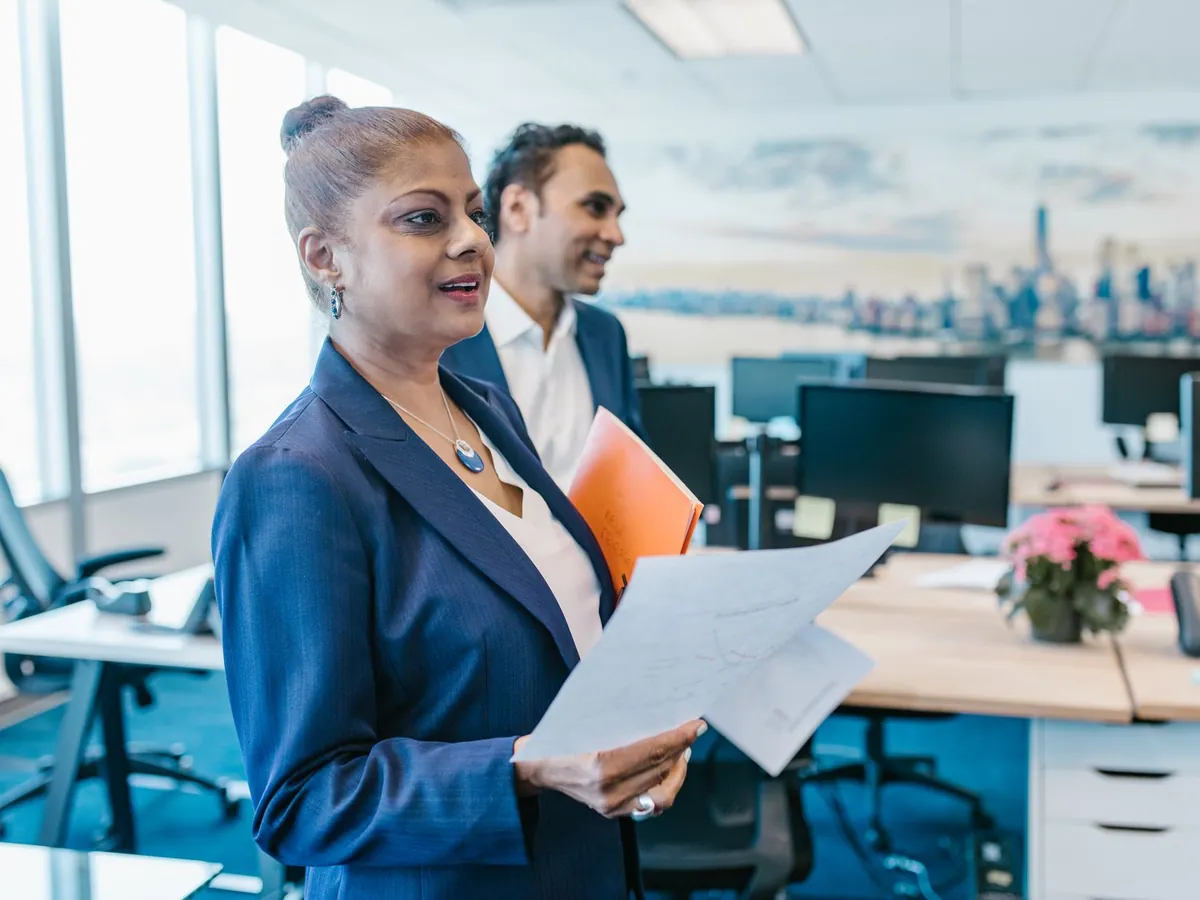 Cadre tenant des documents dans un grand open space d'entreprise