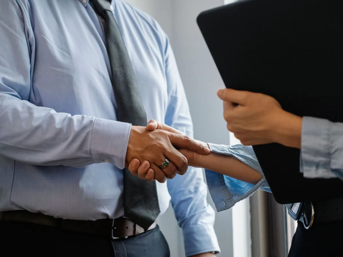 Deux professionnels en tenue de bureau échangeant une poignée de main lors d'un rendez-vous