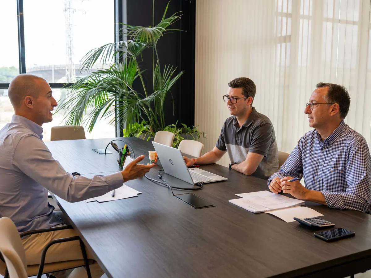 Consultants échangeant autour d'une table de réunion avec un ordinateur portable